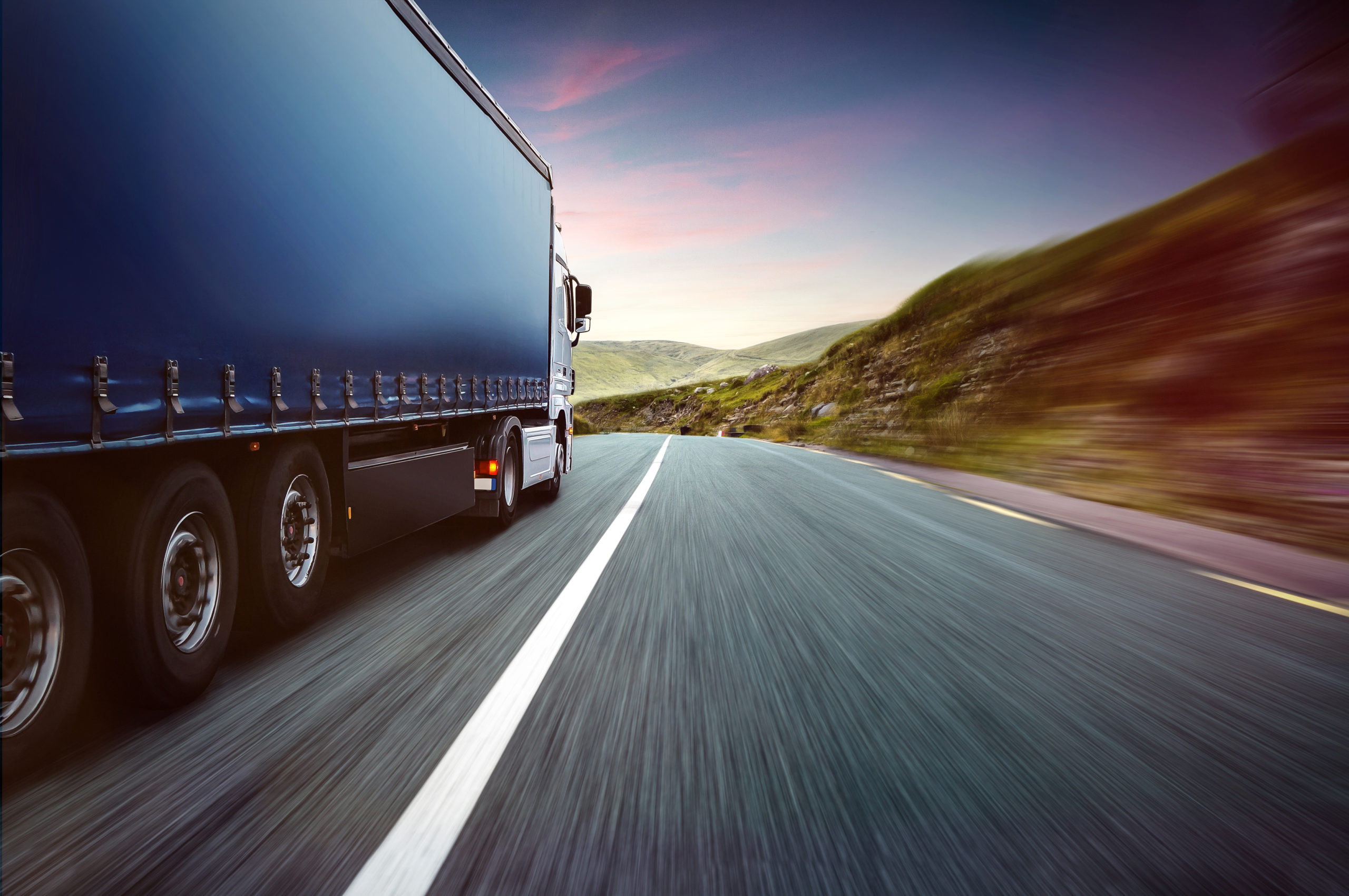Ciężarówka firmy transportowej jedzie szybko na drodze.